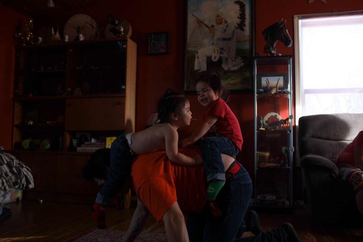 Dylan plays with his two sons in his parents living room on the Maskwacis reservation.
